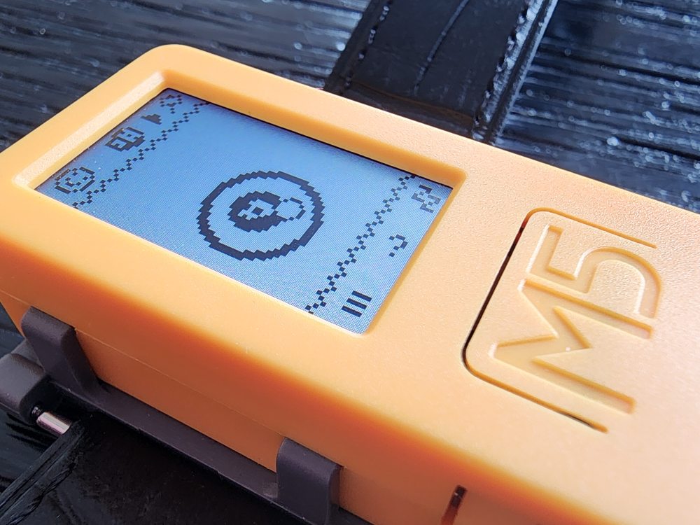 A close-up photo of the M5CStick device on a watch strap running Apocketlypse